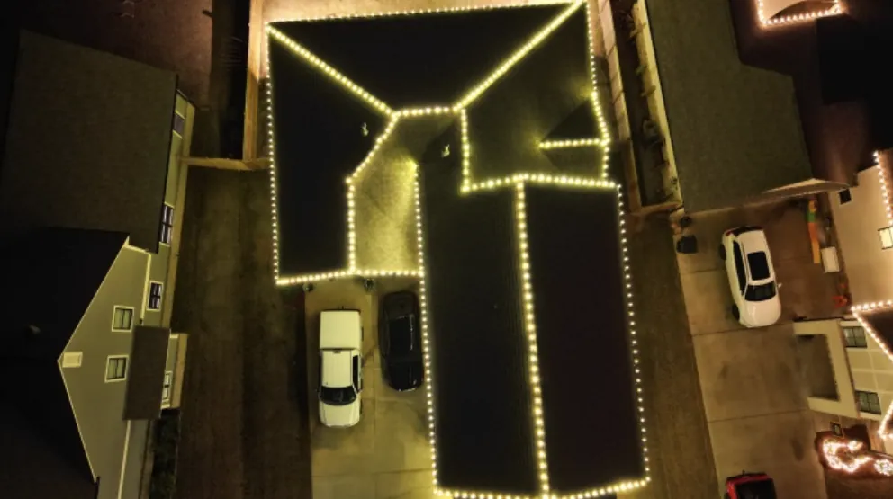 Looking down on a roof edge traced end to end in warm white lights.